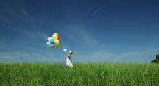 草地上小女孩拿气球跑过